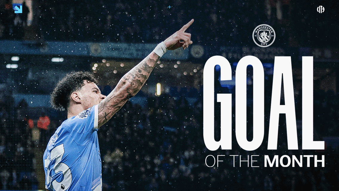 A football player wearing a Manchester City jersey points upwards in celebration of receiving the 'Goal of the Month' award. The Manchester City logo is visible in the background.