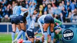 Manchester City women's team players celebrate a goal on the field, with one player lying on the ground. The team's jerseys display sponsors and the team's crest.