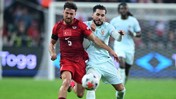 Two soccer players competing for the ball during a match with the player in red representing Turkey.