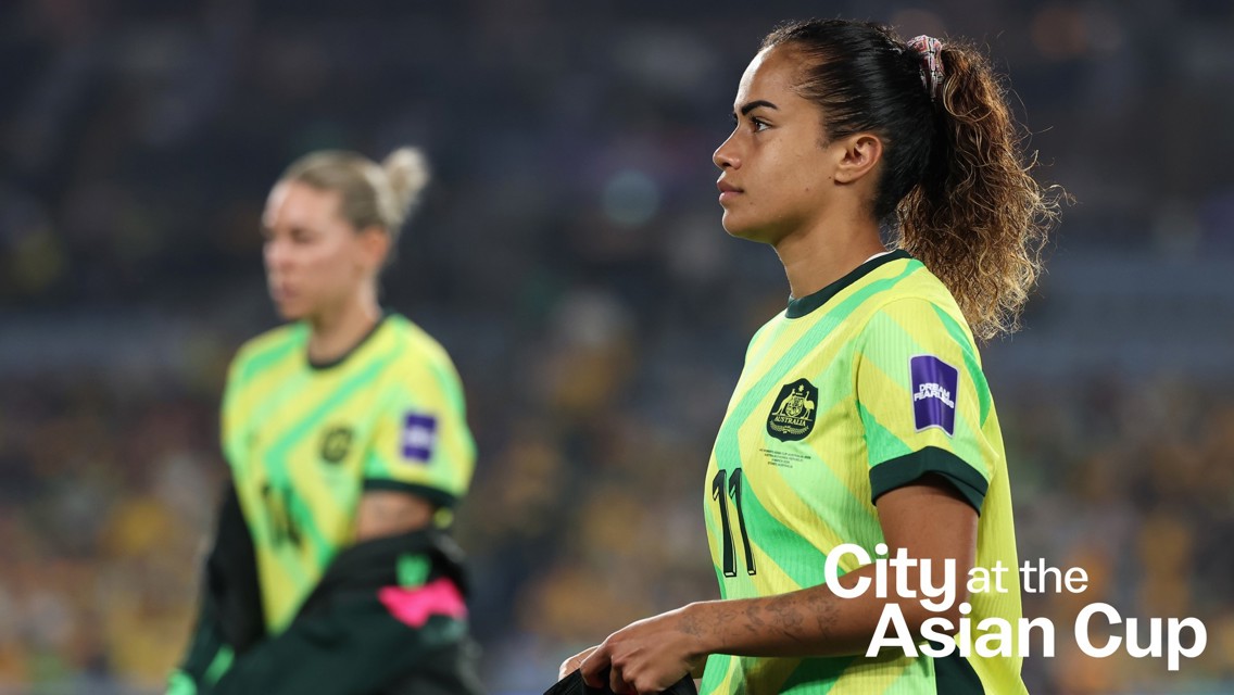 Two players from the Australian team wearing green jerseys, with the text 'City at the Asian Cup' visible.