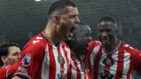 Sunderland AFC players, wearing their red and white kit, celebrate under rain during a game as part of a Premier League match.