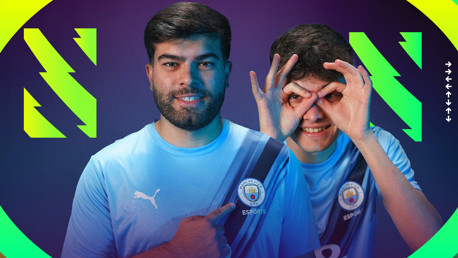 Two individuals wearing Manchester City esports jerseys pointing to the Man City crest.