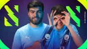 Two individuals wearing Manchester City esports jerseys pointing to the Man City crest.