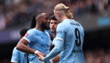Two Manchester City football players wearing light blue kits with the Etihad Airways logo. One player's jersey reads 'Haaland' with number 9. The scene appears to be a celebration or interaction during a match.