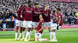 West Ham United players celebrating a goal on the field, wearing maroon jerseys with a crowd in the background.