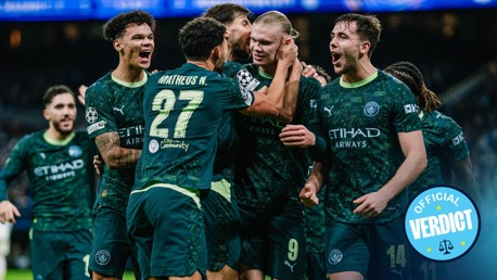 Manchester City players in green jerseys celebrating a goal during a match. The jersey displays the Etihad Airways logo, with number 27 on one player. Faces are blurred.