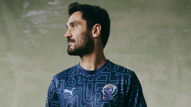 A person wearing a Manchester City eSports shirt with a blurred face. The shirt features a dark blue design with geometric patterns and Puma logo.