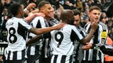 Newcastle United players celebrating a goal during a match. The team's logo and sponsor can be seen on their jerseys.
