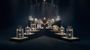 A person is sitting surrounded by various football trophies, including Premier League, FA Cup, and UEFA Champions League trophies.