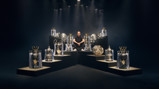 A person is sitting surrounded by various football trophies, including Premier League, FA Cup, and UEFA Champions League trophies.