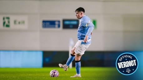 A soccer player in blue kit controlling the ball on a green field with an 'Official Verdict' badge in the corner.