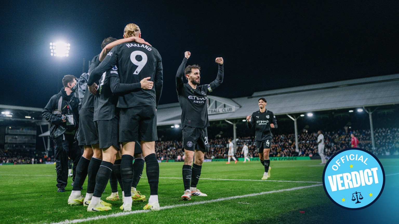 Manchester City players celebrate a goal during a match at Fulham's stadium. Erling Haaland is prominently visible with the number 9 on his jersey.