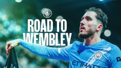 A promotional image featuring Manchester City with text 'Road to Wembley.' The team logo is visible on the blue kit.