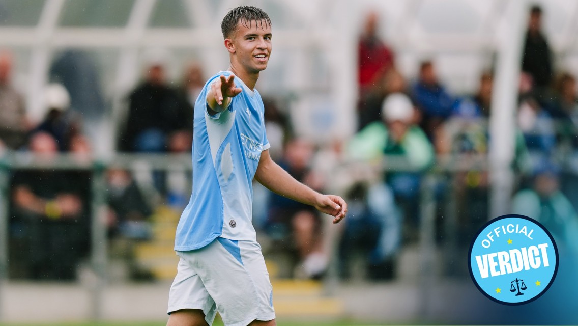 A young male football player wearing a Manchester City kit is pointing towards someone off-camera during a match. The 'Official Verdict' logo is in the lower right corner.