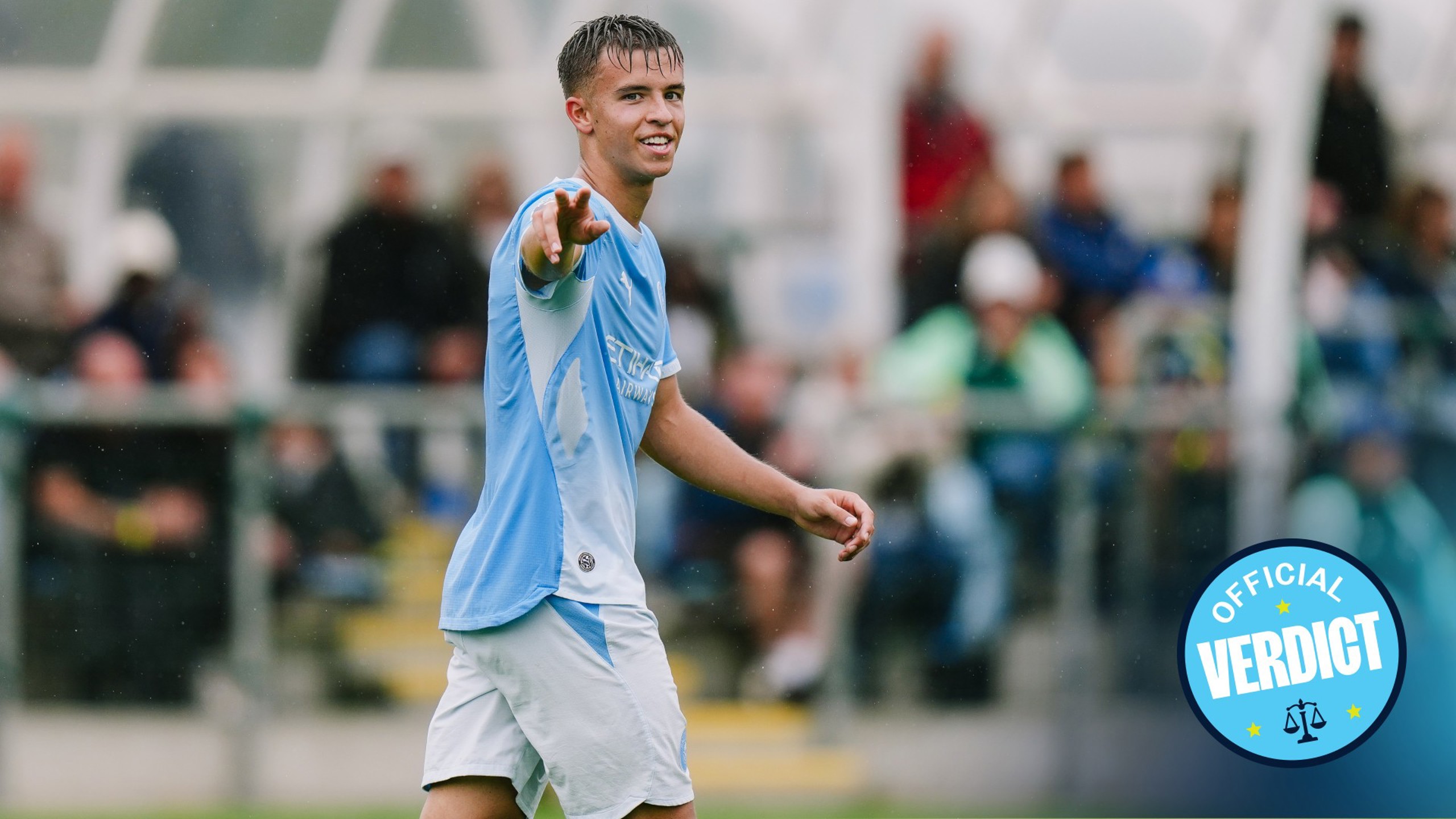 A young male football player wearing a Manchester City kit is pointing towards someone off-camera during a match. The 'Official Verdict' logo is in the lower right corner.