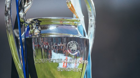 Close-up of the UEFA Champions League trophy with black and blue ribbons attached.
