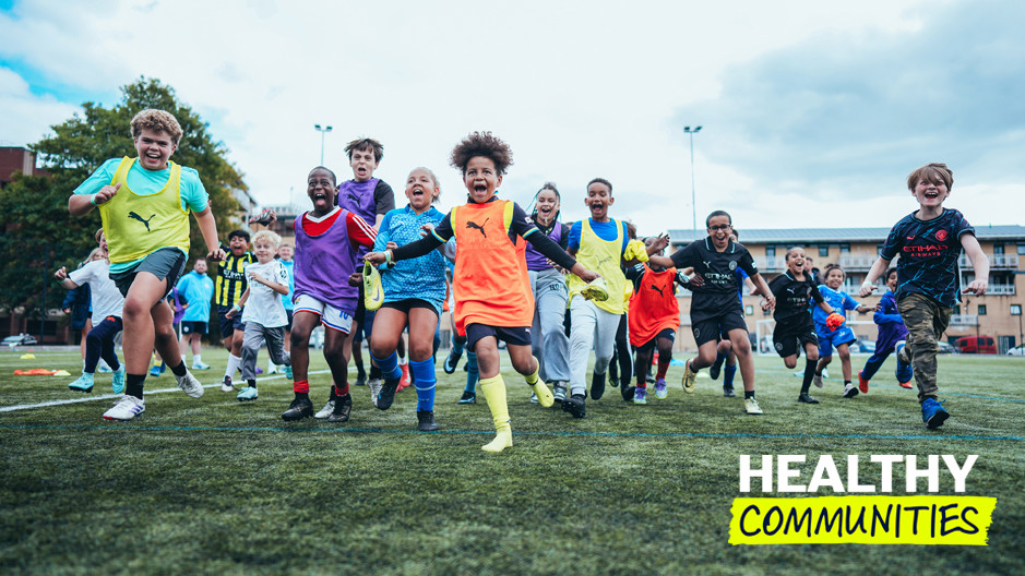 A group of children wearing sports attire running on a soccer field, with healthy communities text overlay.