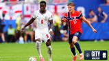 A soccer match between teams from England and Norway. Players in action wearing national jerseys on the field. The City World Cup logo appears in the corner.