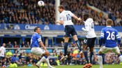 Football match action with Everton and Manchester City players competing for the ball during a Premier League game at Goodison Park. Players are in motion surrounding the ball in the air, with the crowd watching in the background.