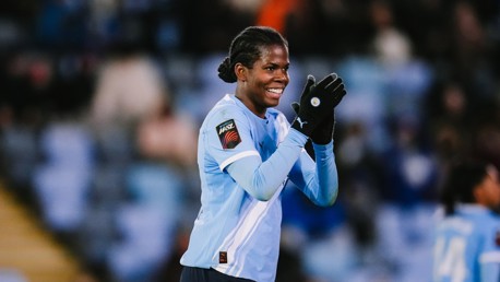 A soccer player wearing Manchester City's light blue kit and gloves clapping during a Women's Super League match.
