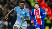 Football match action featuring a player in a Manchester City kit and another in a Paris Saint-Germain kit, both competing on the field.