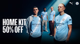 Advertisement for Manchester City home kit showing models wearing the kit. Large text reads 'HOME KIT 50% OFF'. Puma and Manchester City logos are visible.