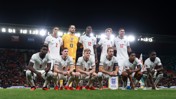 England football team group photo on the field wearing white kits before a match.