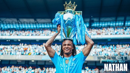 A footballer wearing a blue Manchester City shirt lifts the Premier League trophy over their head. The stadium is filled with fans, and the text 'Thank You Nathan' is visible in the image.