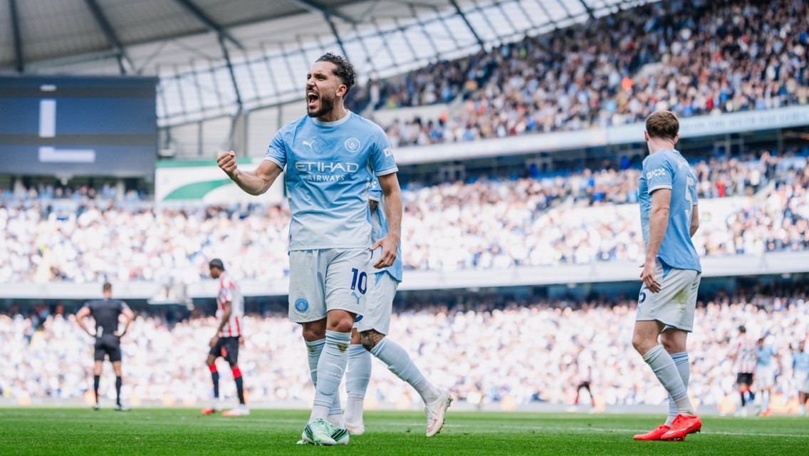 Manchester City player celebrating a goal during a football match at Etihad Stadium.