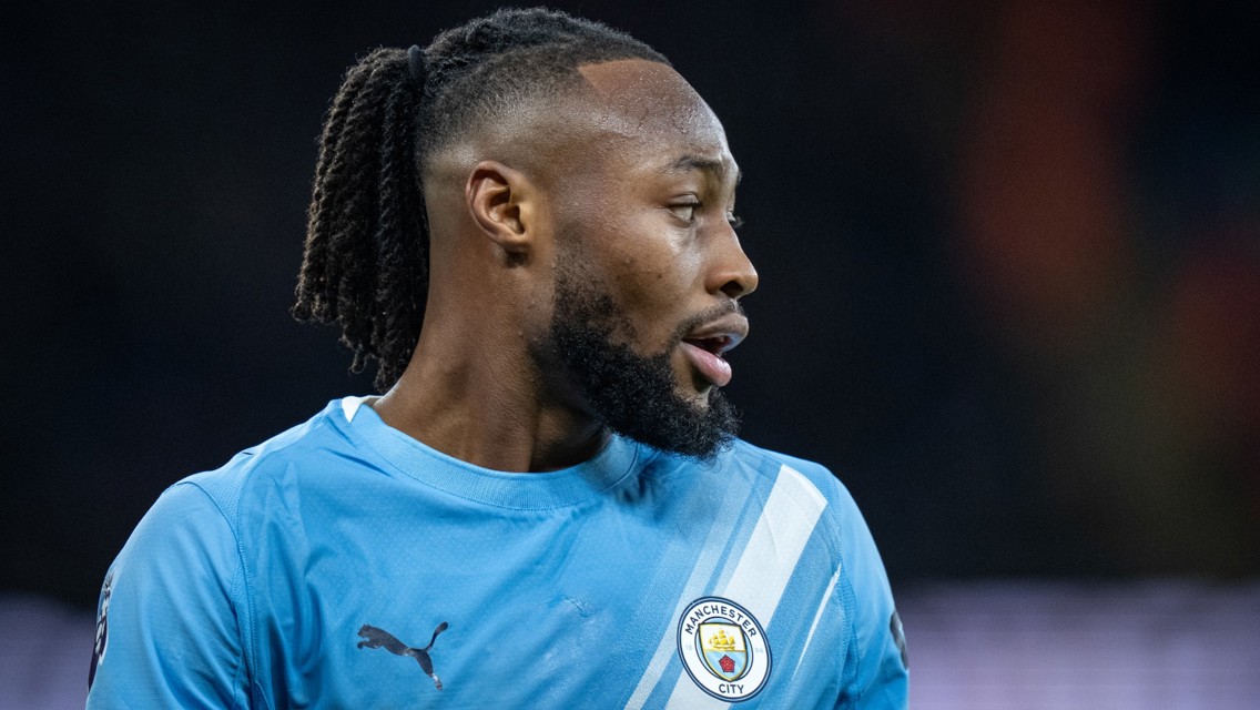 A football player wearing a Manchester City kit with blurred face, featuring the Manchester City logo on the chest.