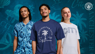 Three individuals in Manchester City-themed summer wear: a blue patterned shirt, a navy tee with 'Manchester City' and a palm design, and a white tee with 'City'.