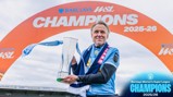 A person holding a trophy in front of a Barclays WSL Champions 2025-26 sign.