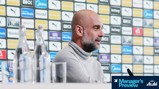 A person with blurred face speaking at a press conference with Manchester City logos displayed behind.