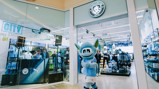 Manchester City's mascot stands outside the club store, surrounded by team merchandise and decorations promoting Christmas deals.