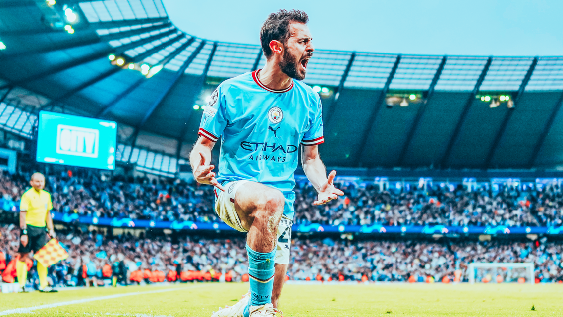 A Manchester City player celebrates a goal at the Etihad Stadium, wearing the team's sky blue kit sponsored by Etihad Airways, with a large crowd visible in the background.