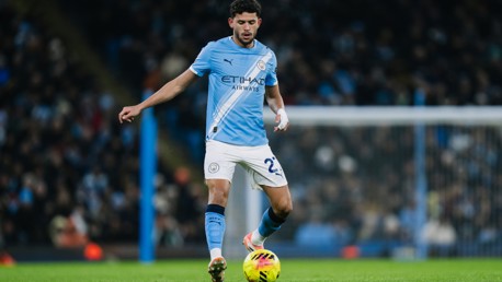 A Manchester City player in action on the field wearing a light blue kit during a match.