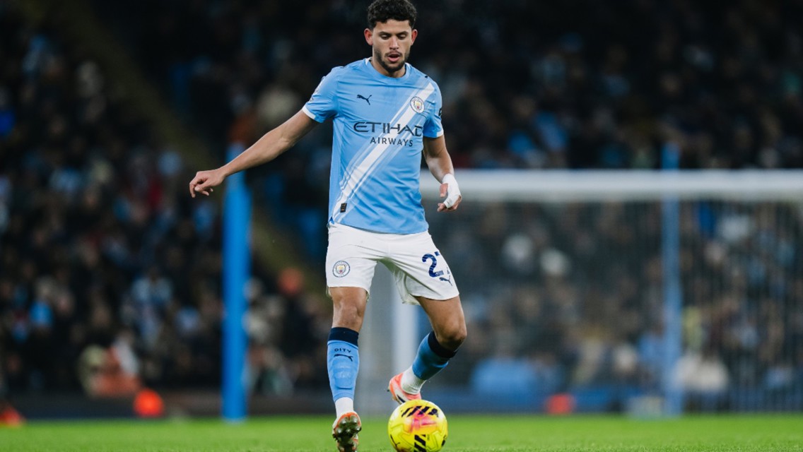 A Manchester City player in action on the field wearing a light blue kit during a match.