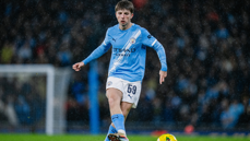 A football player wearing the Manchester City kit with number 59, playing on a rain-soaked field.