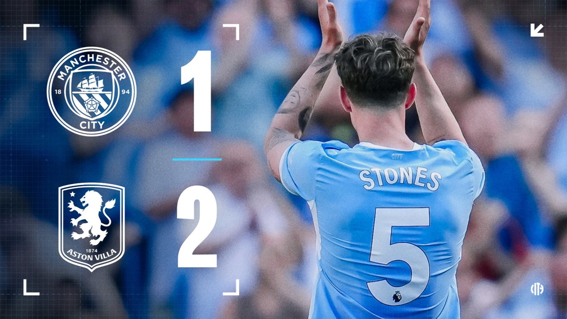 Scoreboard showing Manchester City 1 - 2 Aston Villa. A player with 'Stones' and number 5 on their jersey is clapping.
