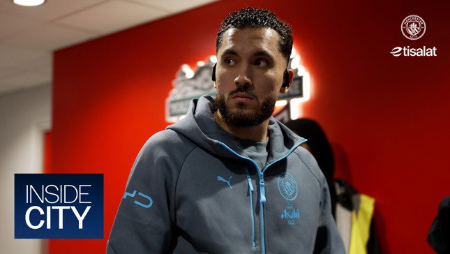 A person in a Manchester City tracksuit inside a building. The image includes Manchester City and Etisalat logos.