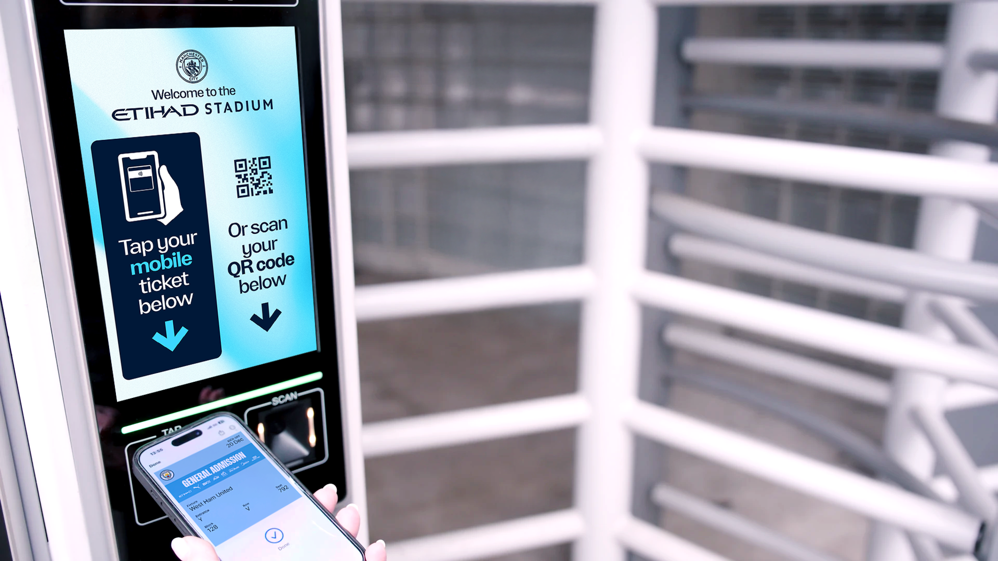 A mobile ticket is being used at a turnstile in the Etihad Stadium. The screen displays instructions to tap or scan a QR code for entry.