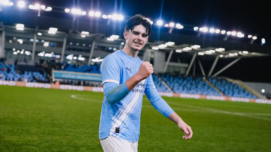Football player in Manchester City kit celebrating on the pitch with a blurred face.