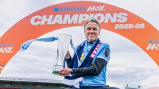 Person holding a trophy under an arch labeled 'BARCLAYS WSL CHAMPIONS 2025-26'.
