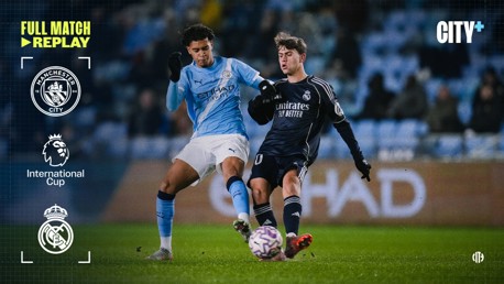 Two soccer players from Manchester City and Real Madrid compete for the ball during an International Cup match. The image features logos of Manchester City and Real Madrid with text indicating a full match replay available on City+.