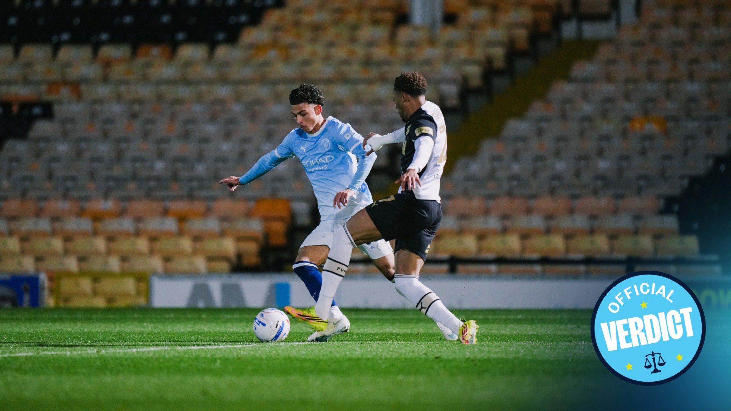 A soccer match scene with a Manchester City player in light blue kit and an opponent in black and white kit, both contesting for the ball on a field.