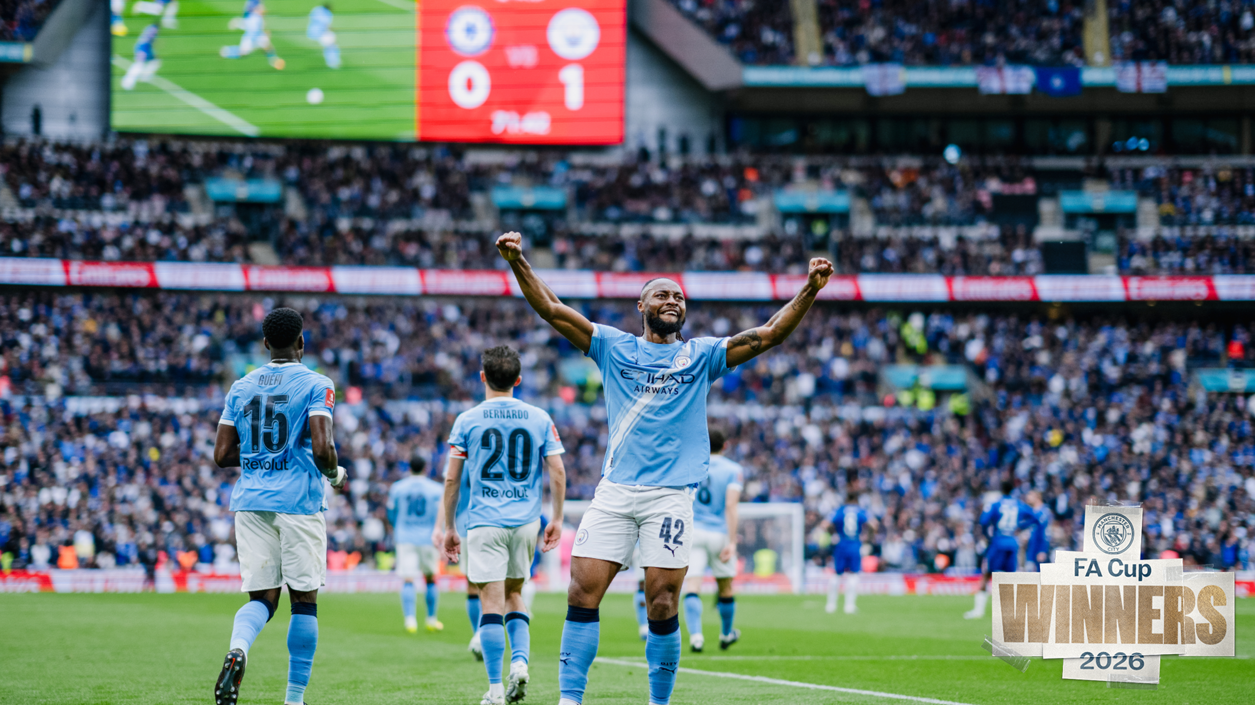 Manchester City player celebrating FA Cup win with score 1-0 against Chelsea, surrounded by team at Wembley Stadium.
