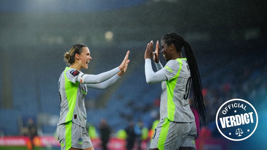Two female soccer players in green and gray jerseys high-fiving on a rainy field. One wears '9' with the name 'BORN' on her back. An 'Official Verdict' stamp is in the bottom right corner.