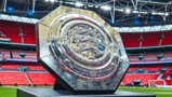 The FA Community Shield trophy displayed on a football field.