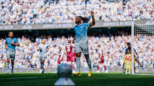Football player in a Manchester City jersey celebrates a goal with an arm-raised gesture during a match.