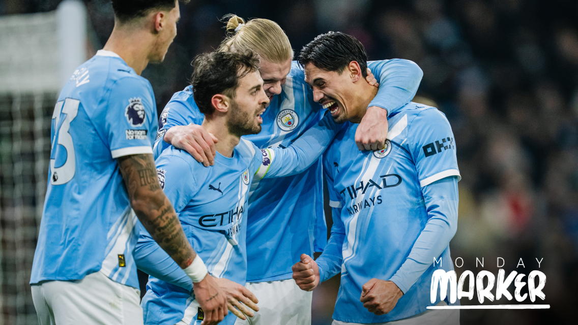 A group of Manchester City players in blue kits celebrating during a football match with 'Monday Marker' text.